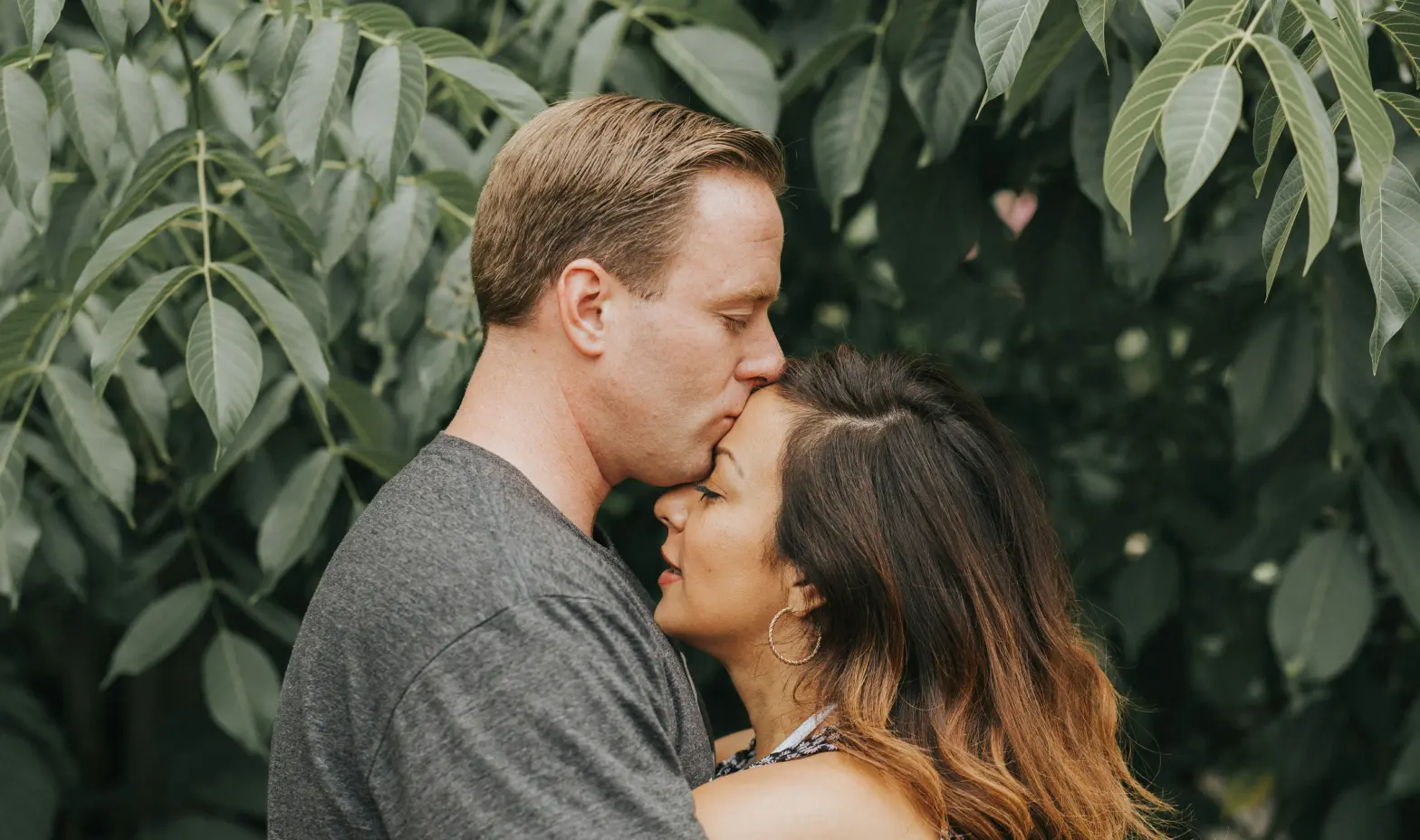 A happy couple shares a romantic moment in a lush park, showcasing their love in charming engagement photos.”