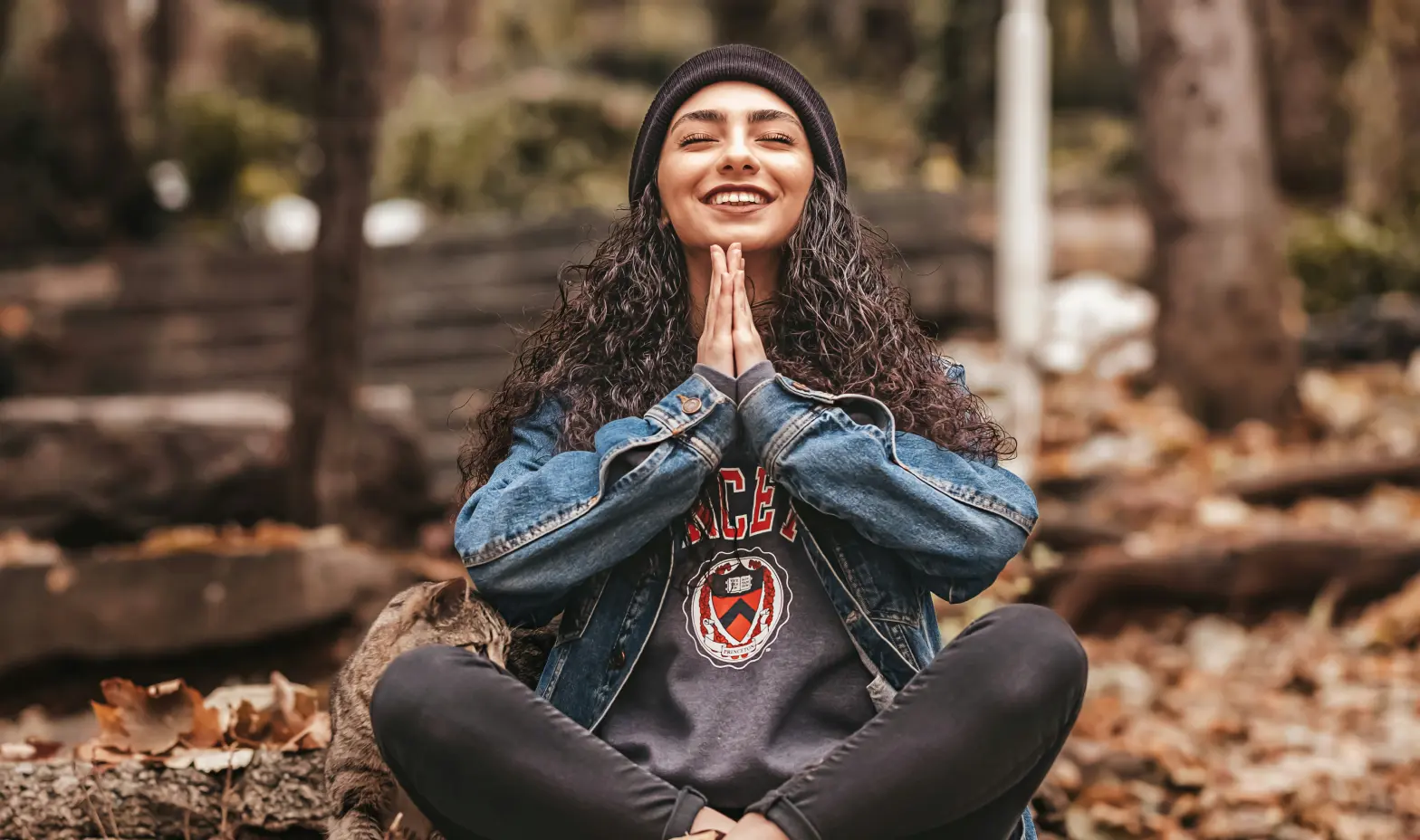 A woman enjoys a moment of calm nestled among tall trees in a green forest.