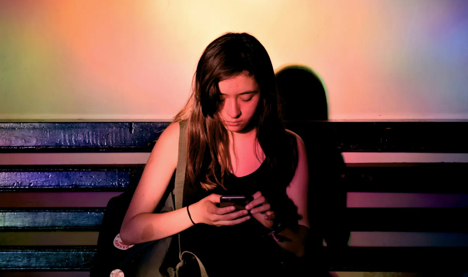 A woman on a bench, engaged with her cell phone, surrounded by a peaceful outdoor setting.