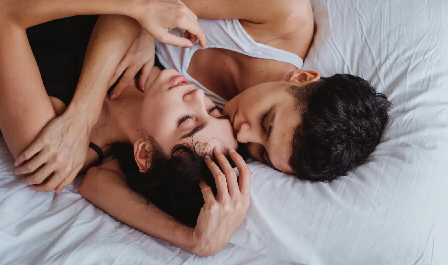 A couple lies on a bed, sharing a peaceful and intimate moment.