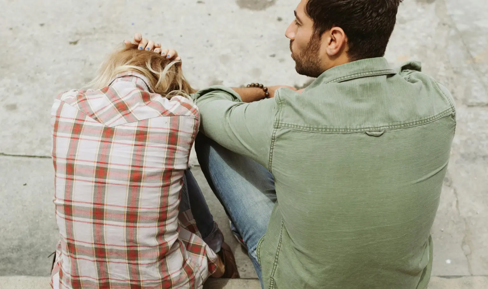A couple sits on the steps of a building, engaged in conversation.