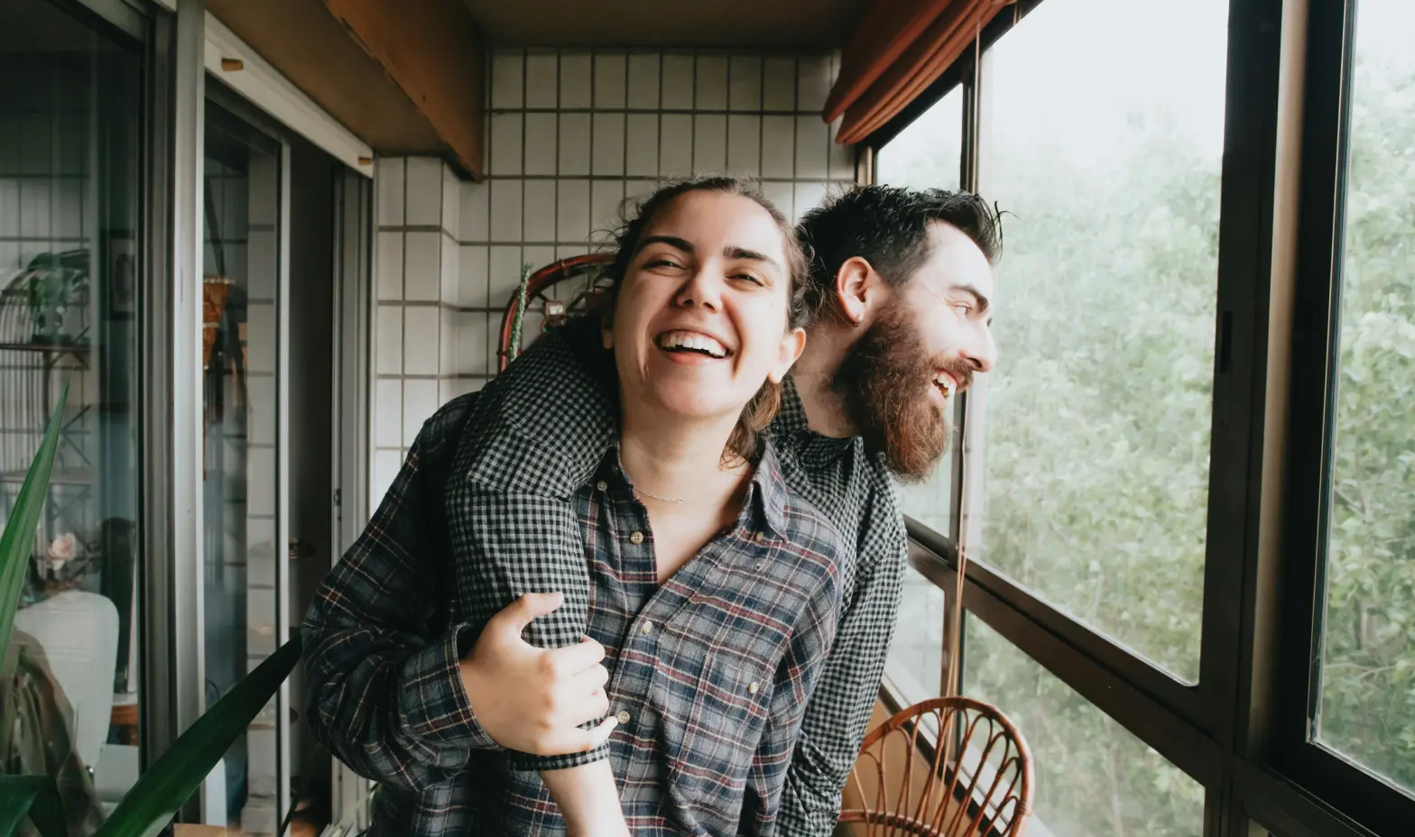 A smiling man and woman stand together on a balcony, enjoying the view and each other's company.