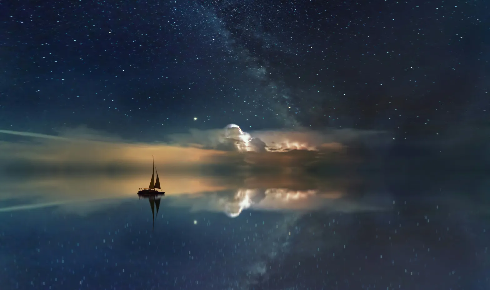 A sailboat in the water with the milky way in the background