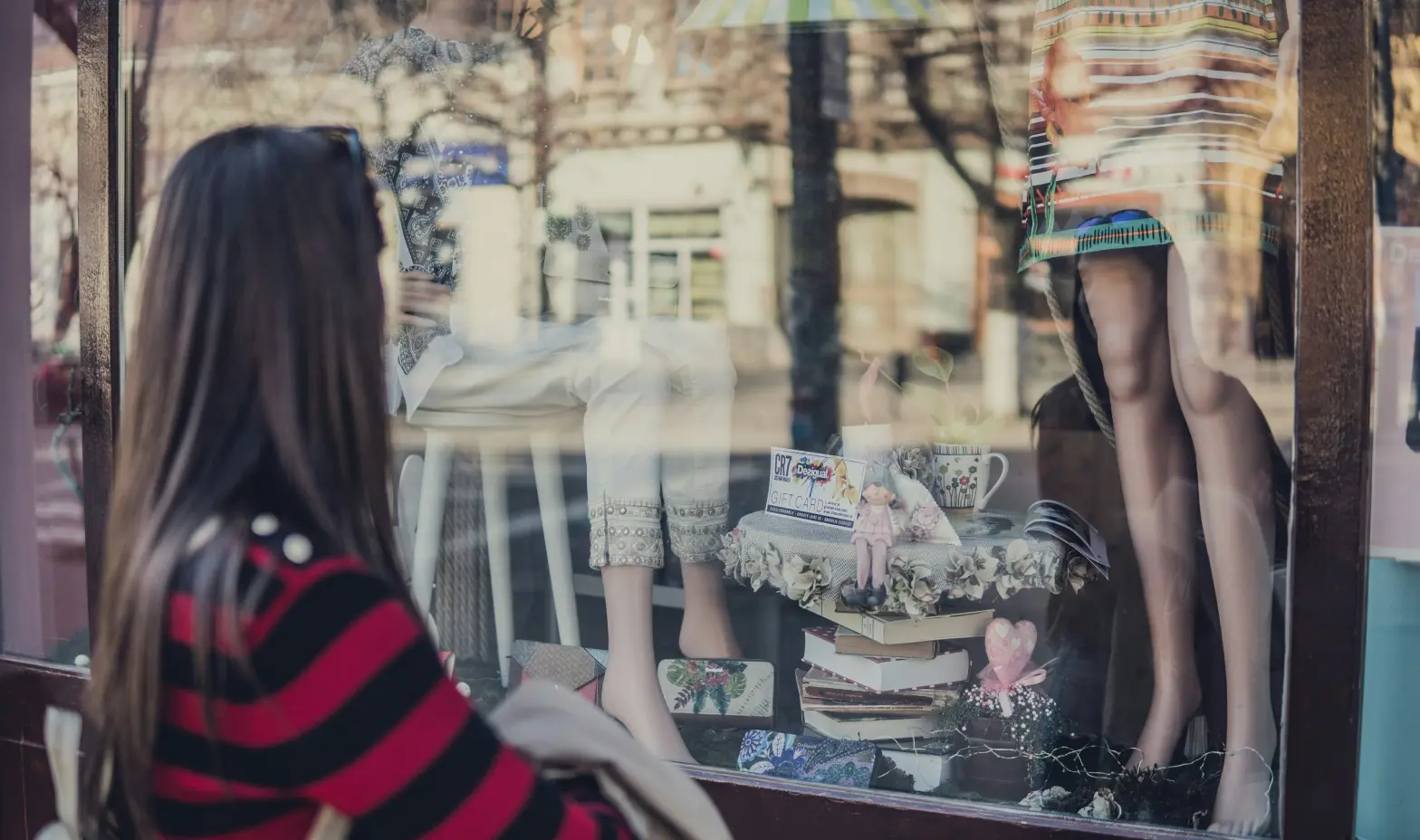 A woman admires a stylish clothing display in a store window.