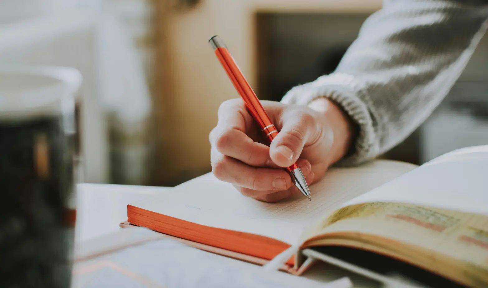 Someone writing in a notebook with a pen