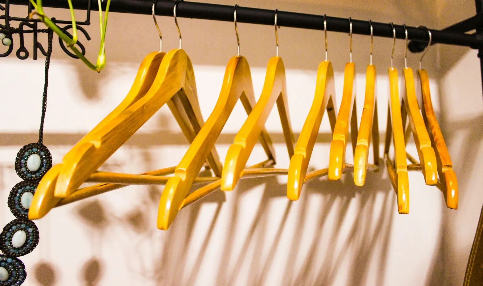A wooden hanger rack featuring several hangers and a small potted plant for a cozy vibe.