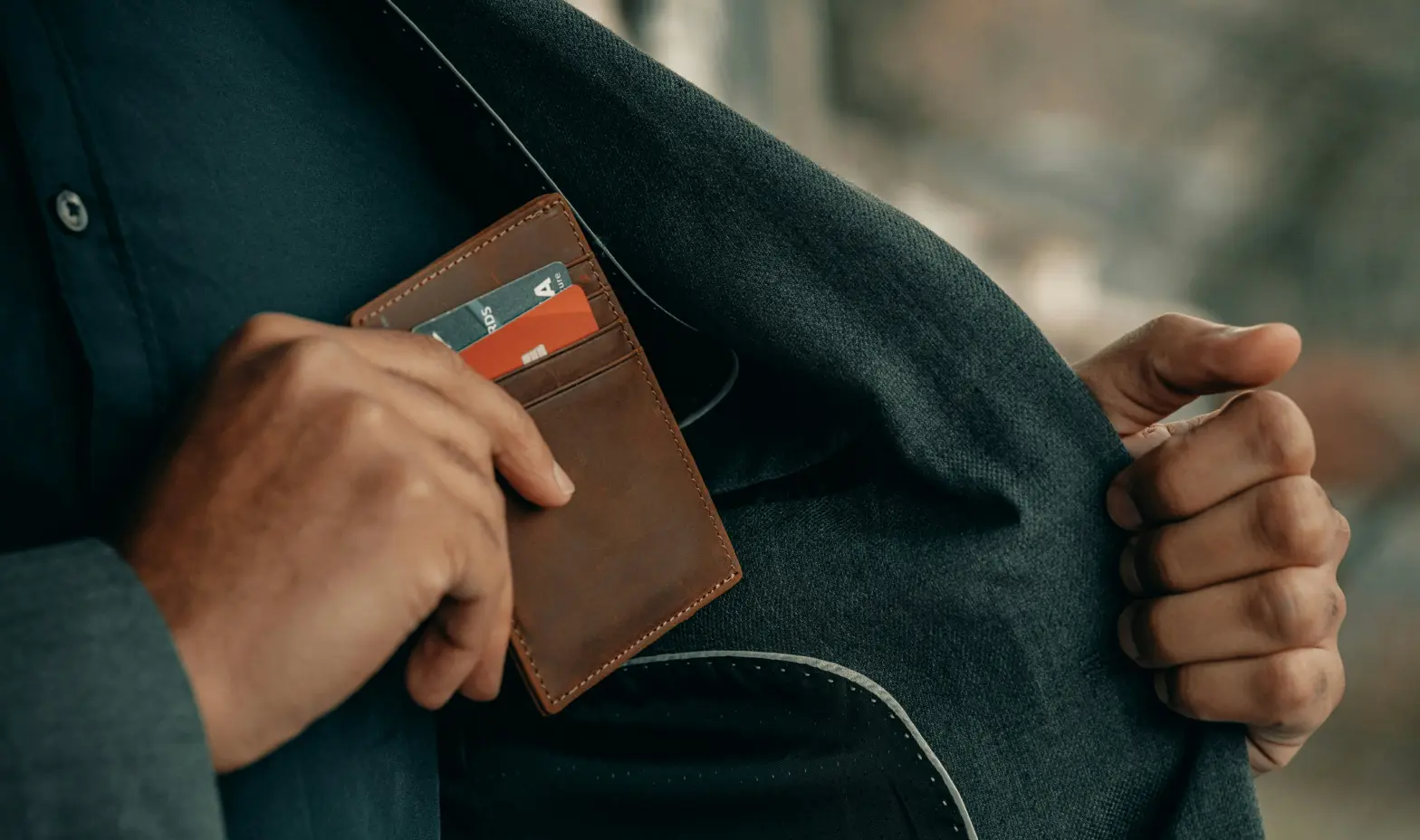 A man holds a wallet open, revealing a credit card inside.