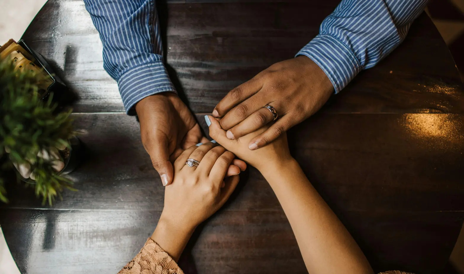 A couple holding hands across a table, sharing a moment of connection and intimacy.