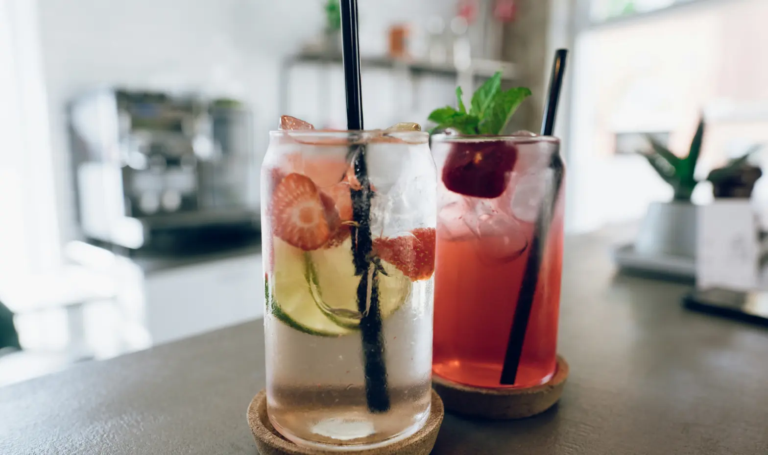 Two colorful drinks with straws sit on a bar counter, ready to be enjoyed.