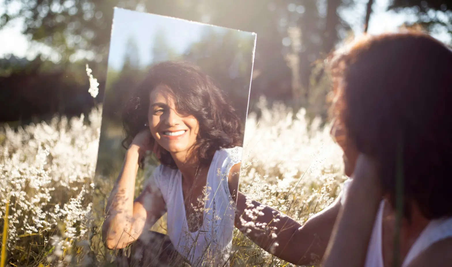 A woman gazes at her reflection in a mirror, contemplating her appearance.