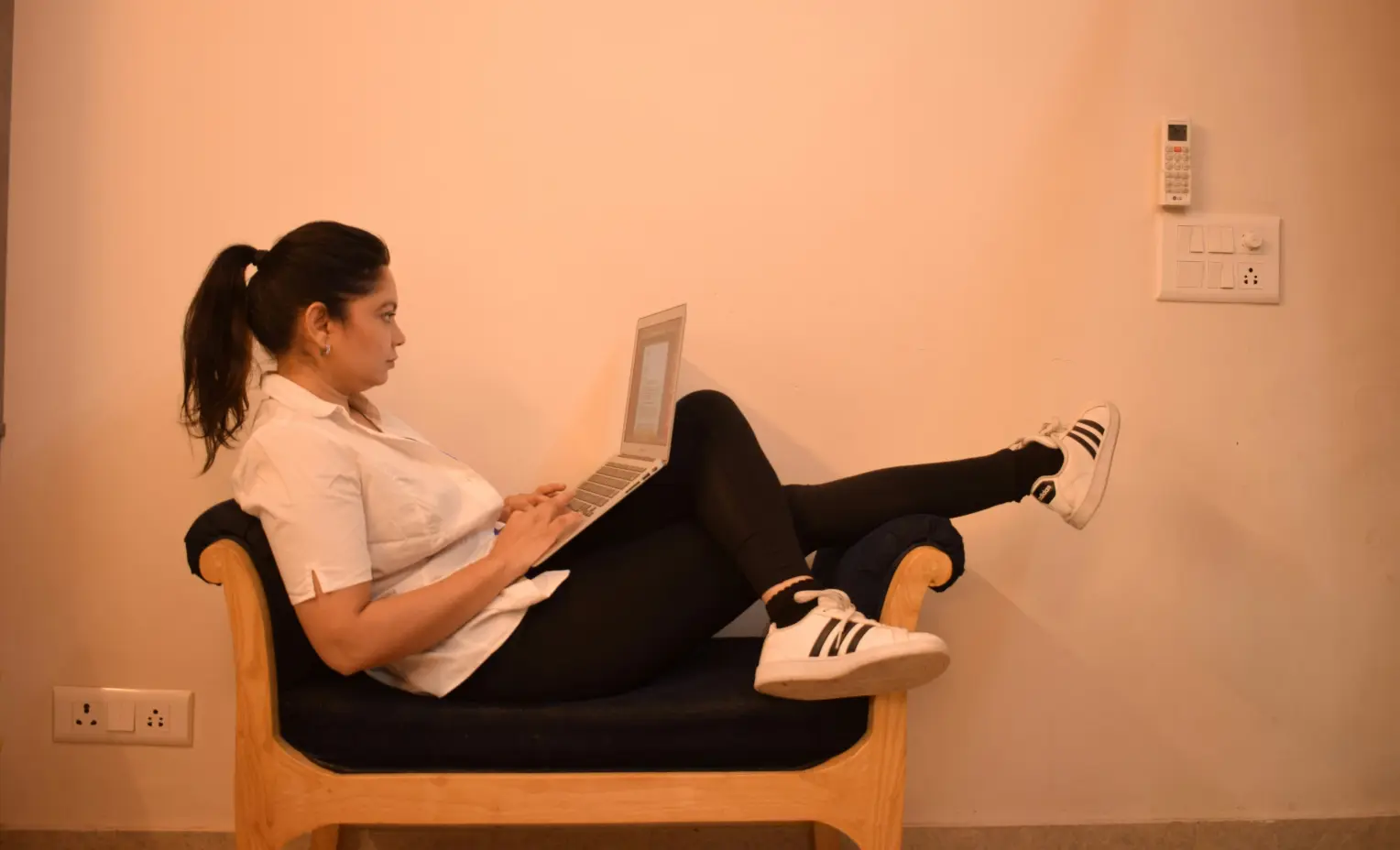 A woman comfortably seated in a chair, using her laptop for work or leisure.