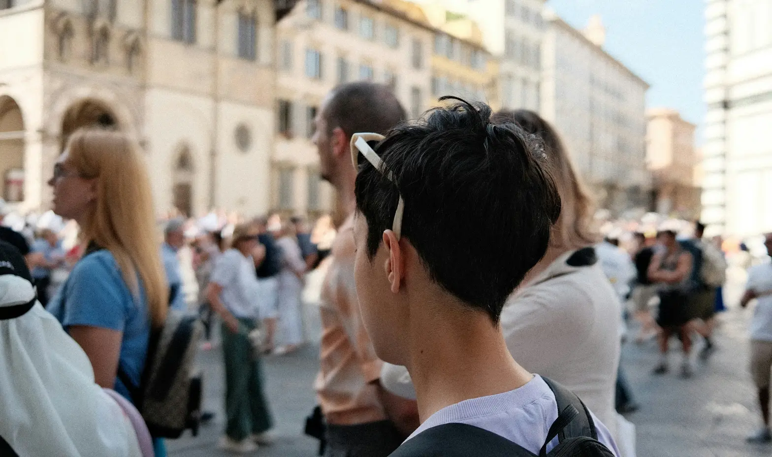A crowd of people gathered in a lively city, surrounded by tall buildings and busy streets.