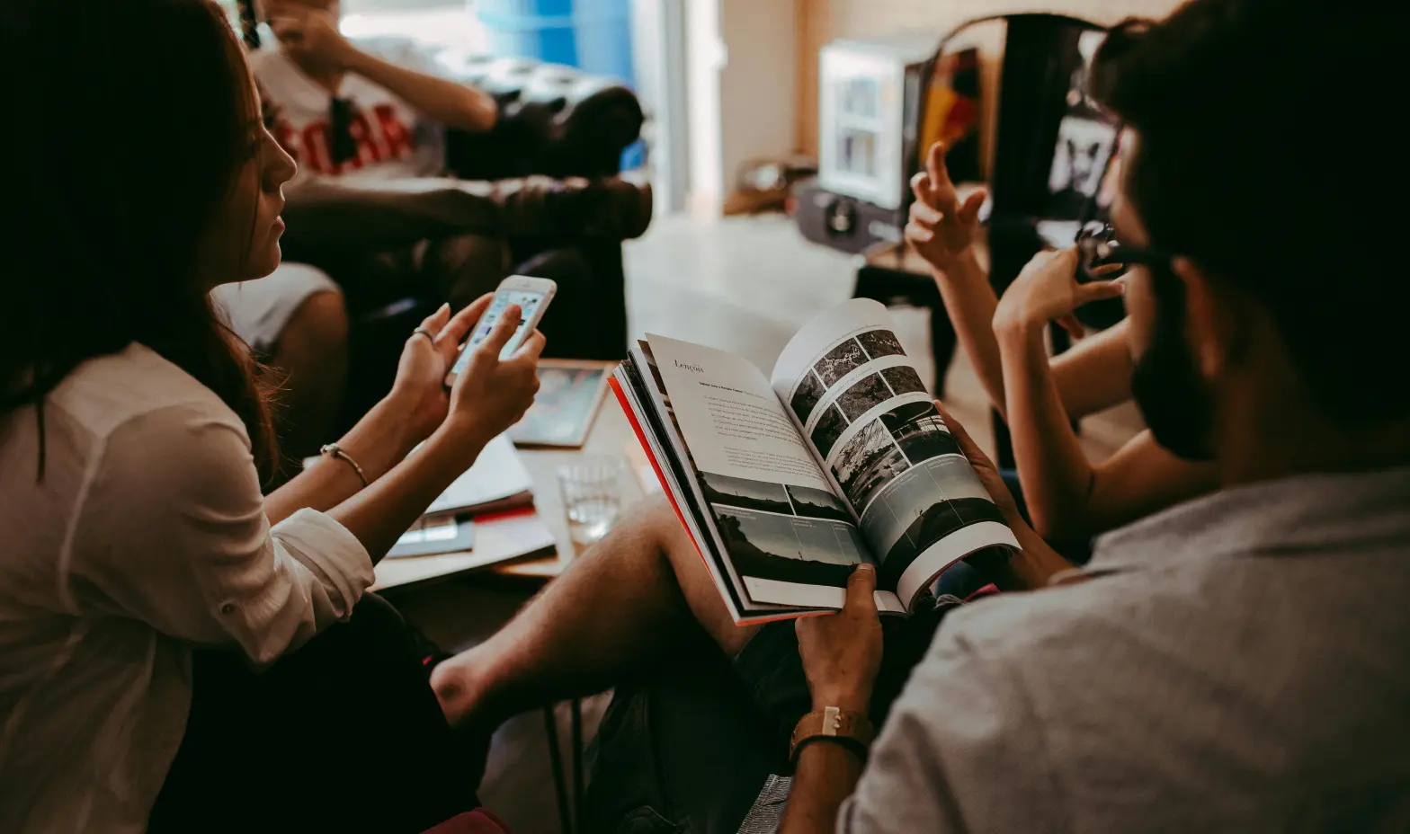 Several individuals around a table, focused on a journal, enjoying a collaborative reading experience.