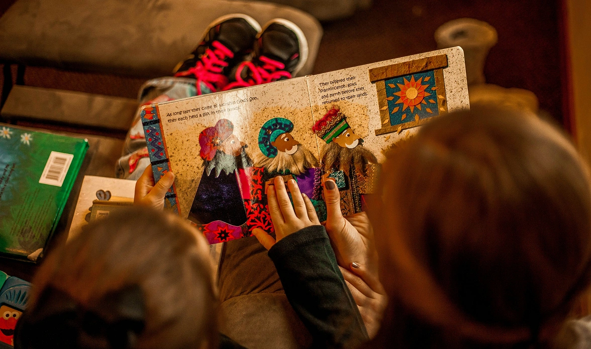 two_children_reading_a_book_on_a_sofa