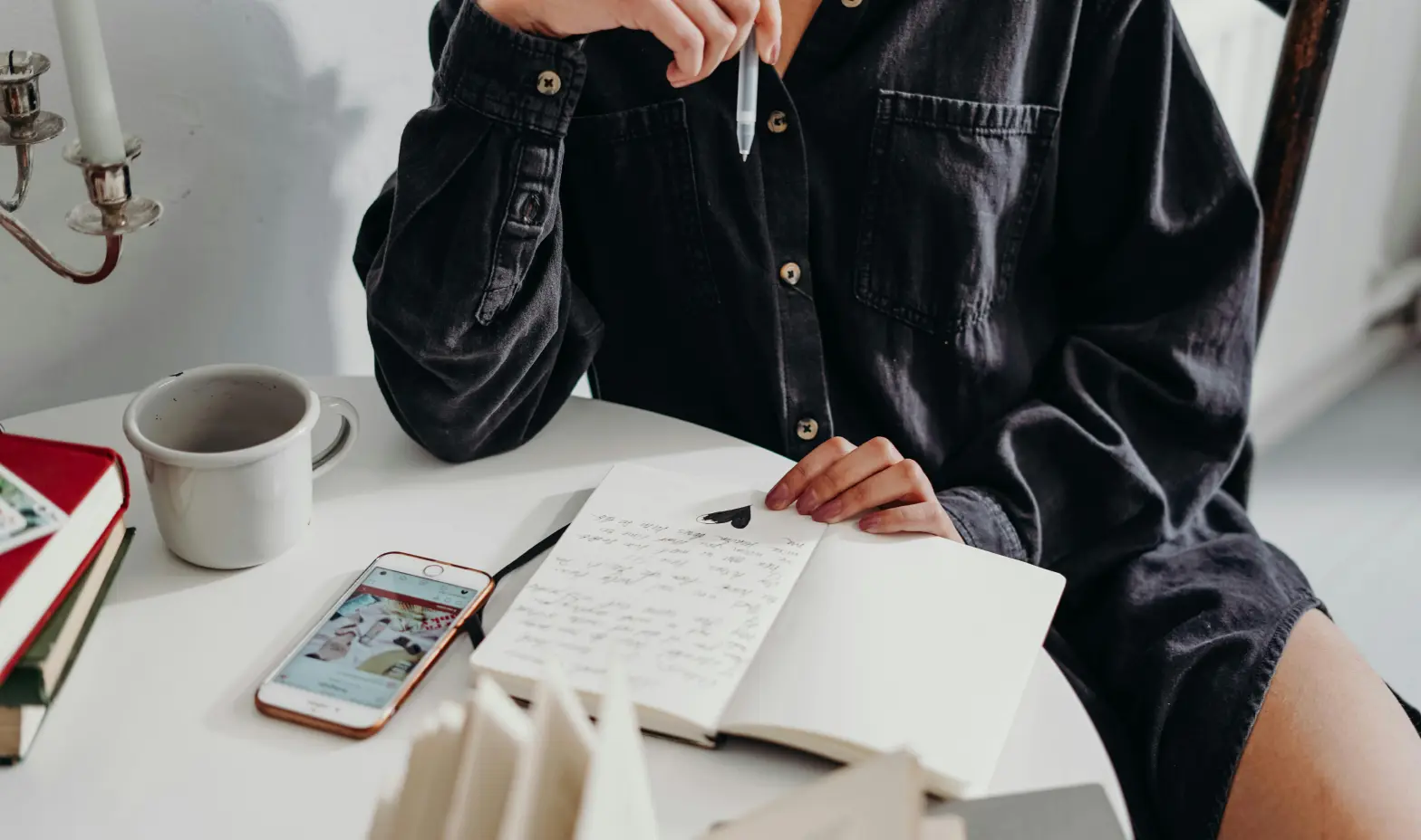 A person sitting at a table with a notebook and cell phone